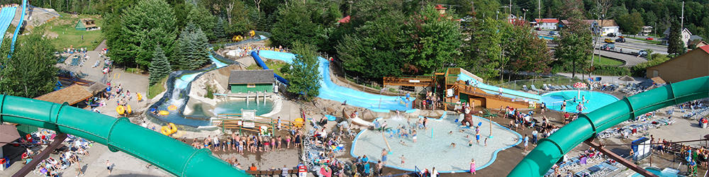 An overview of the park showing large water slides, a lot of people, pools and the lazy river