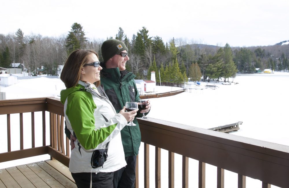 A couple smiling while overlooking the lake during the winter season.