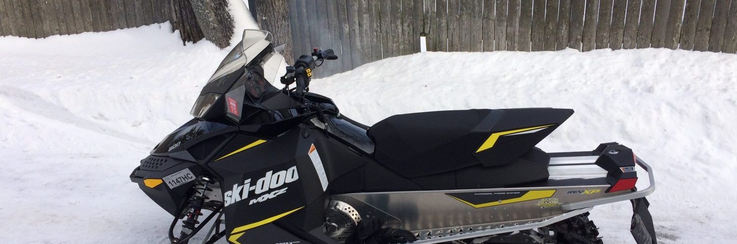 A black and yellow snowmobile is ready to hit the snowmobiling trails.