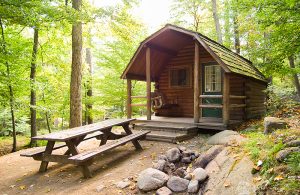 One of the cabin rentals available at the Camping Resort. This cabin has a picnic table and a wooden swing in the front.
