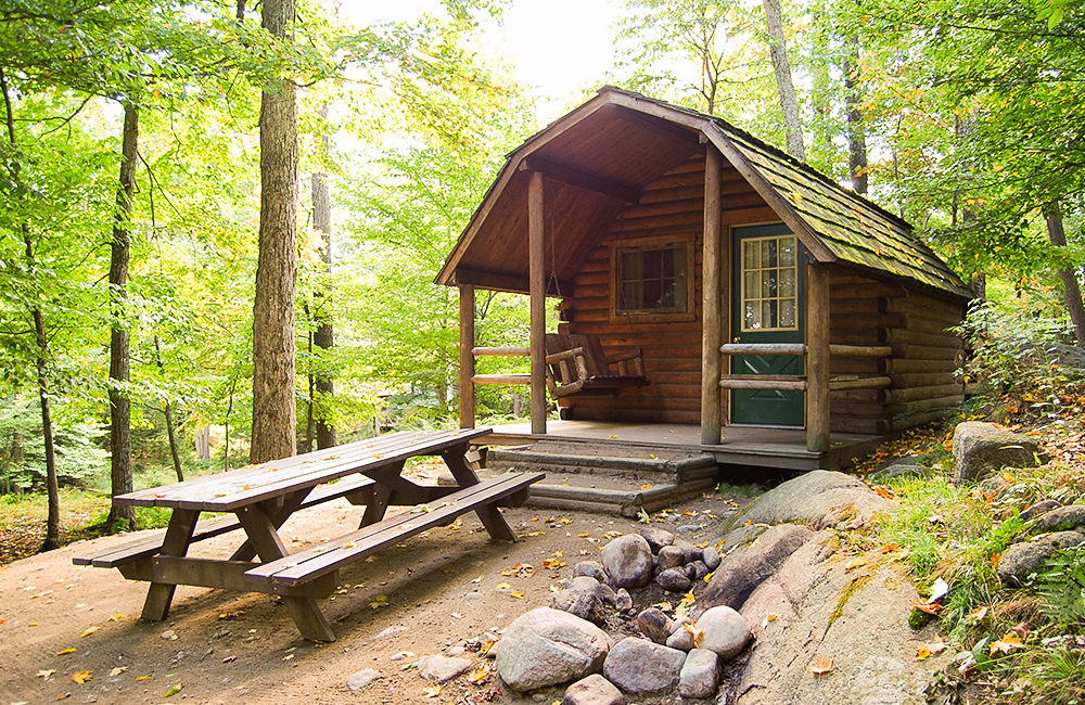 One of the cabin rentals available at the Camping Resort. This cabin has a picnic table and a wooden swing in the front.