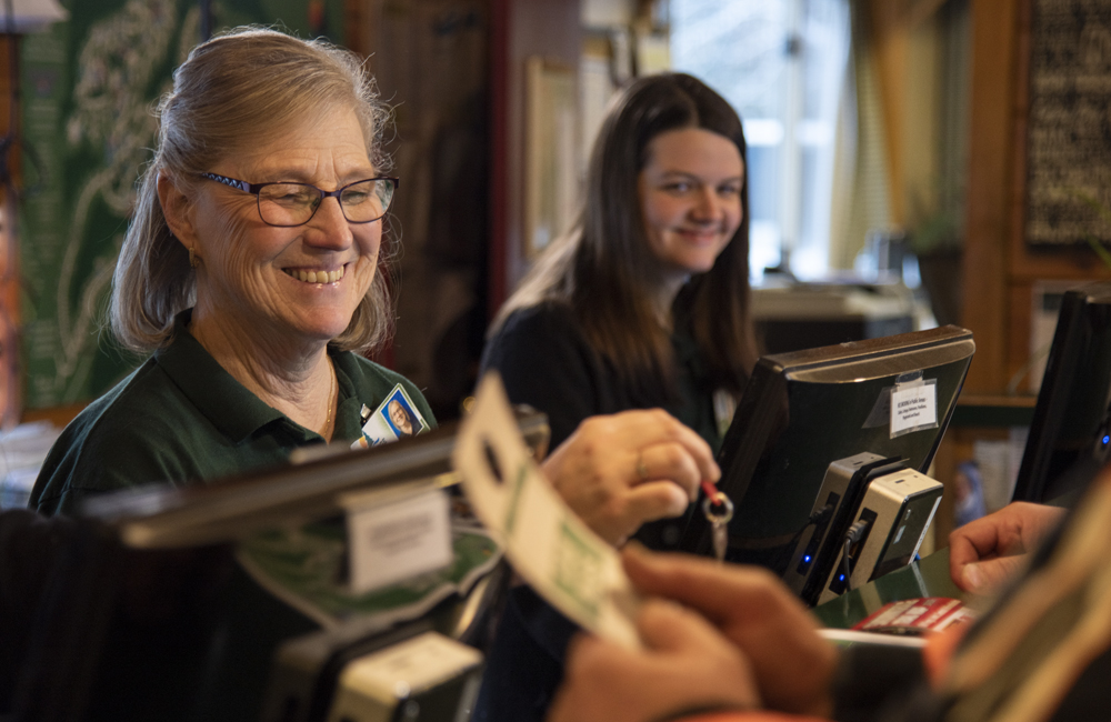 Two of the workers at the main desk smiling and helping the customers.