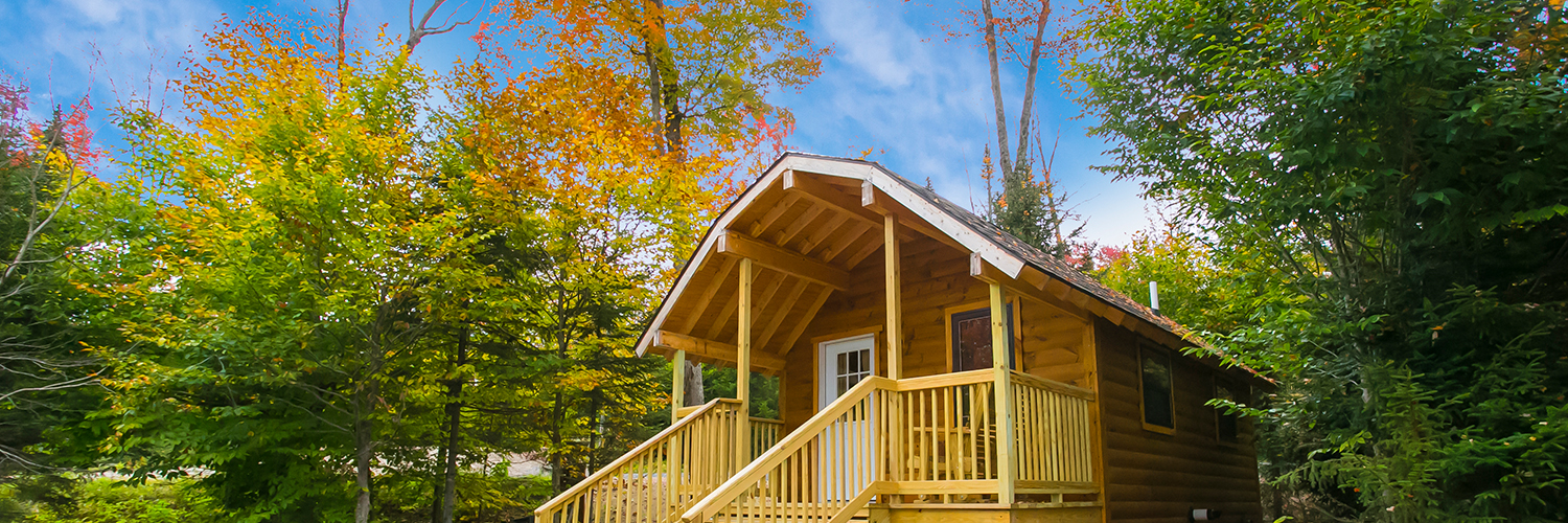 A picture of one of the cottages available for rent. The cottage has a porch and a wooden swing in the front.