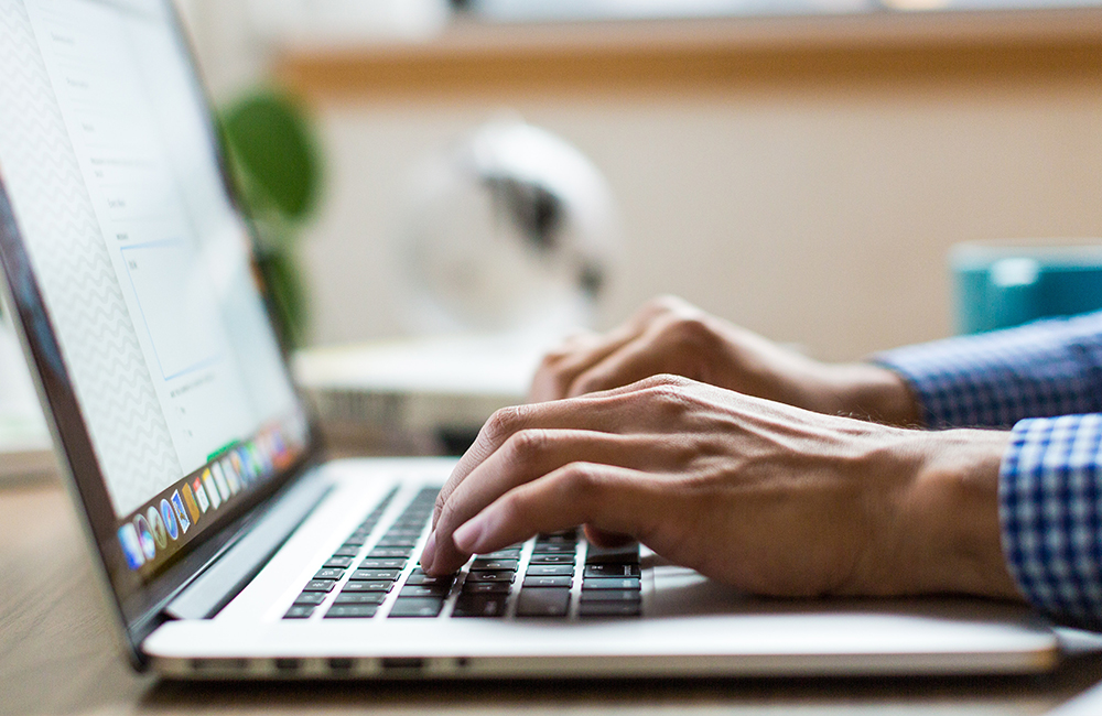 Picture of a person typing on their laptop.