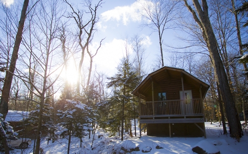 A cabin in the snow with the sun shining down