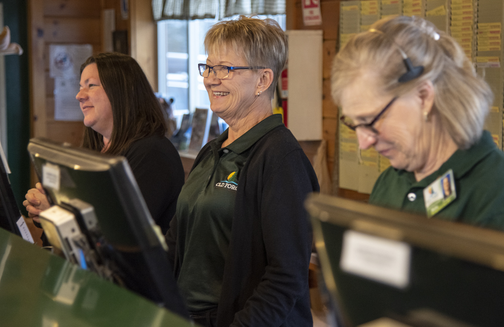 Three ladies smiling while working at the main desk at the Camping Resort.