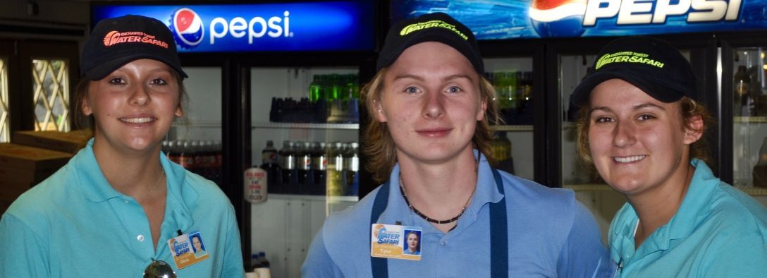 Three water safari employees smiling at the camera with soda coolers in the background