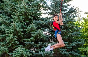 A girl smiling as she slides down the zip-line at Calypso's Cove.