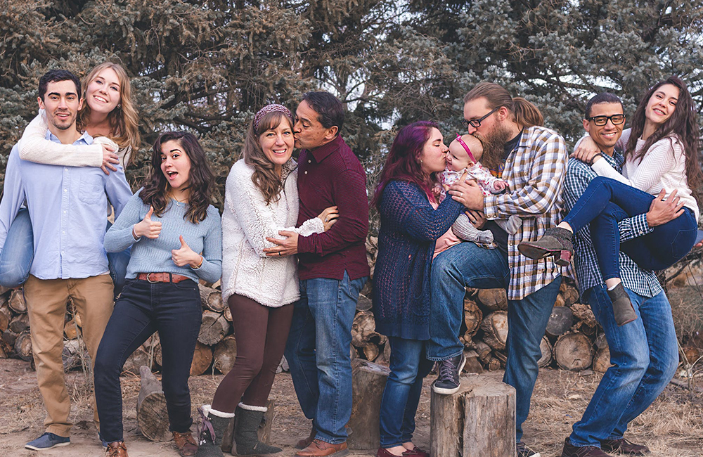 a family hugging and standing next to each other smiling at the camera