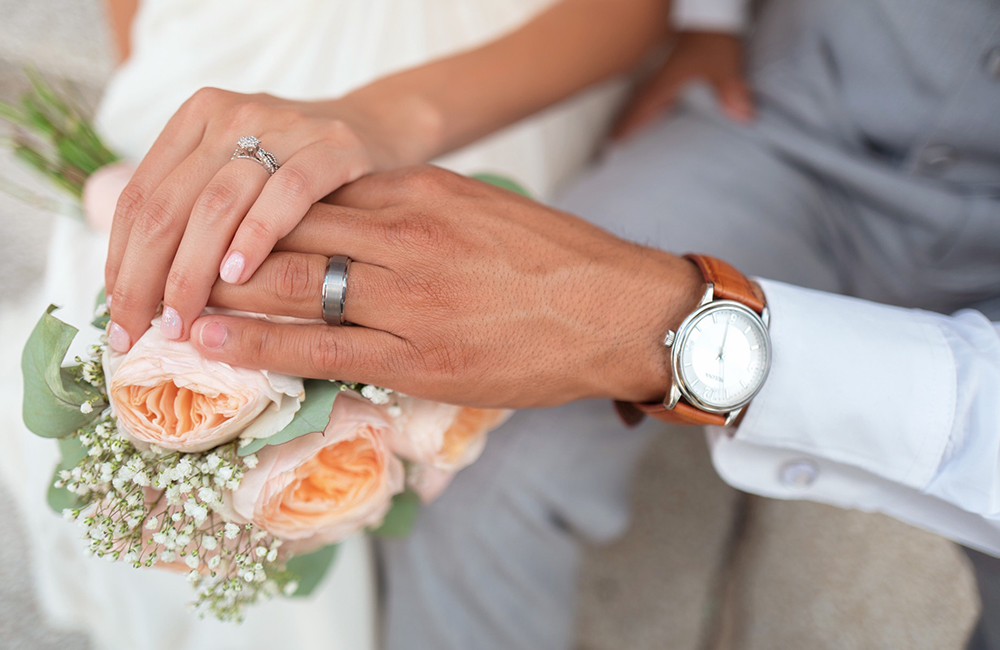 the hands of the bride and groom on the wedding bouquet