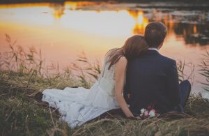 bride and groom sitting and looking out over the water at sunset