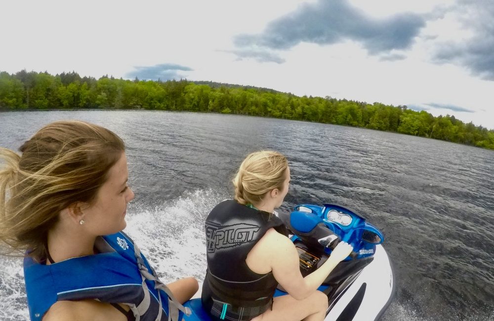 Two girls riding a jet-ski on the lake.