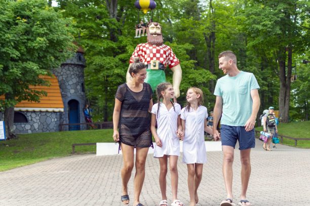 family of 4 holding hands walking in front of Paul Bunyan statue